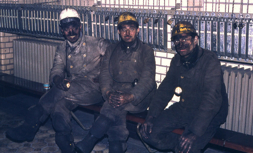 Portrait of firefighters sitting on bench against wall