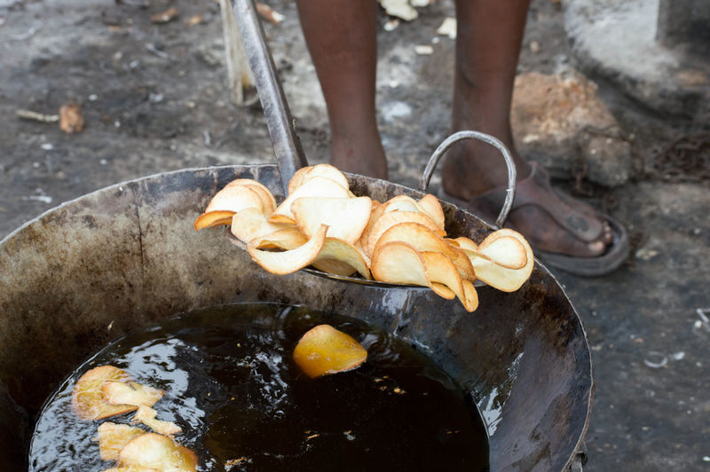 Low section of man frying potato chips outdoors