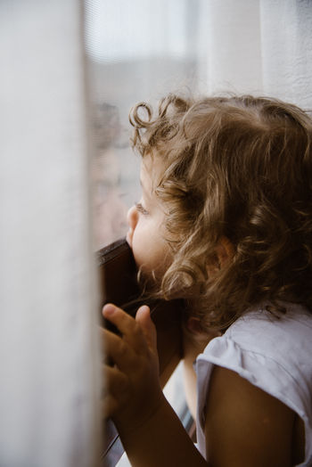 Side view of girl looking through window
