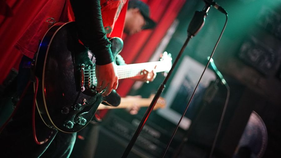 Midsection of man playing guitar on stage