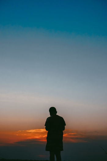 Rear view of silhouette man standing against sky during sunset
