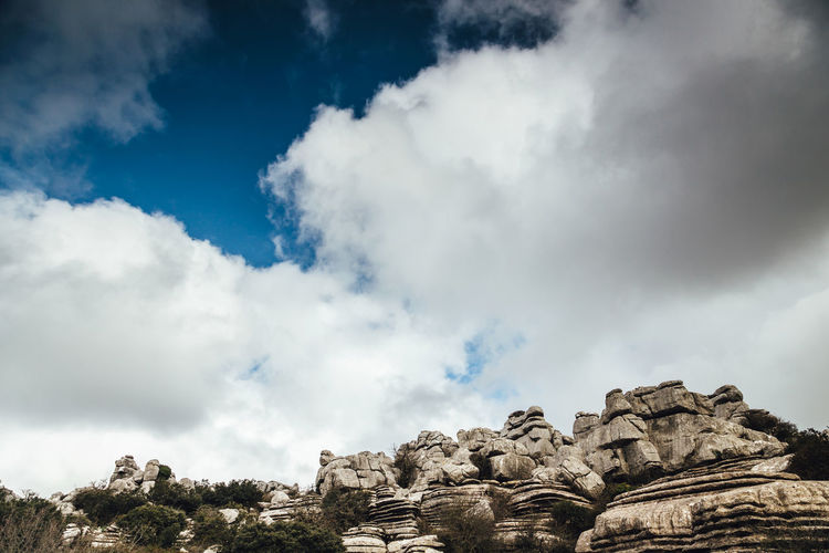 Low angle view of rock formation against cloudy sky