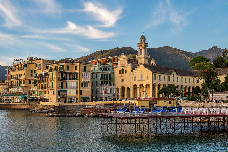 Buildings by river against sky
