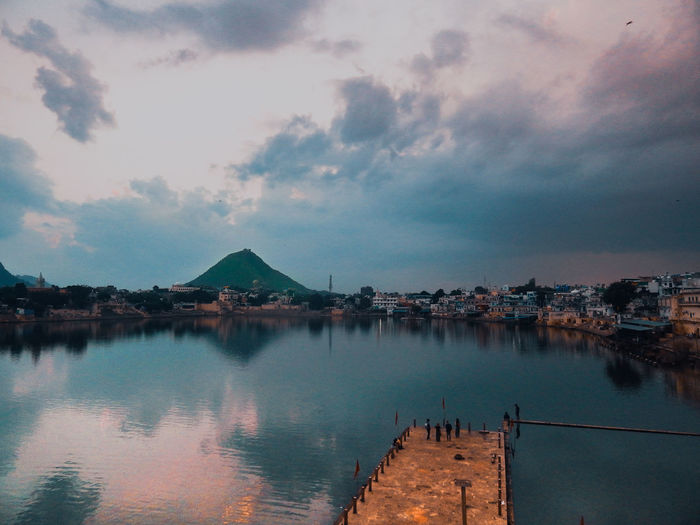 Scenic view of lake by houses against sky during sunset