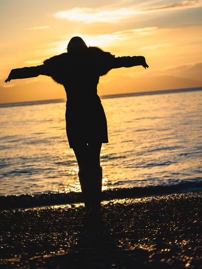 Silhouette woman standing at beach during sunset
