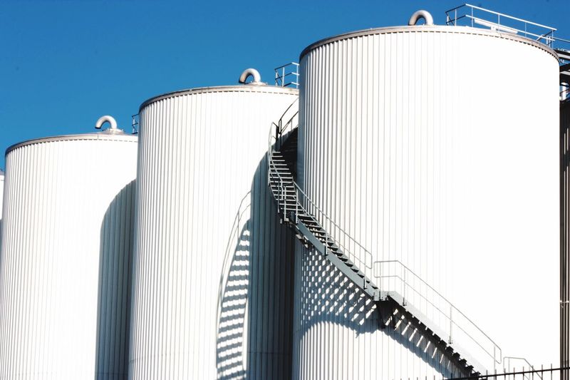 Low angle view fuel storage tank against clear blue sky