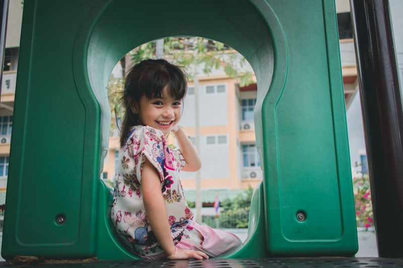 Portrait of cute smiling girl sliding in playground