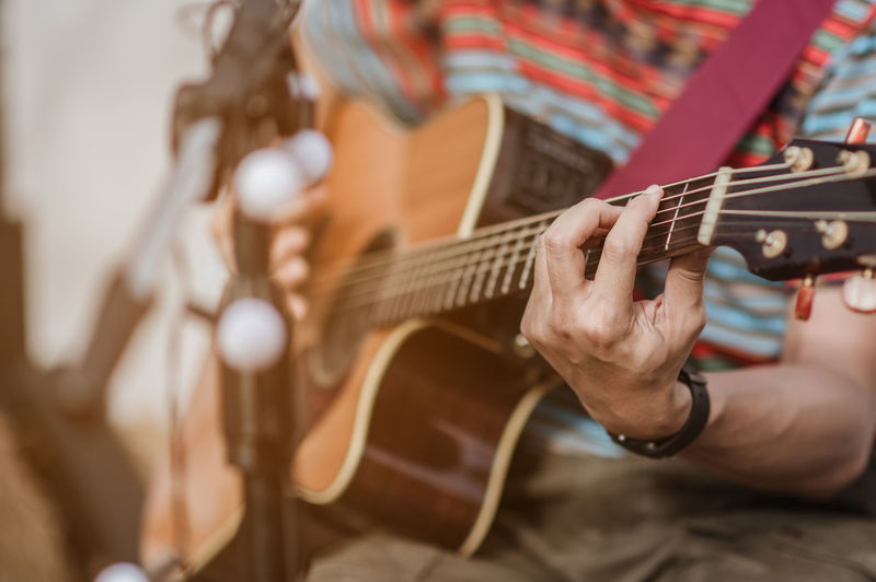 Midsection of man playing guitar at music concert
