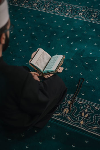 High angle view of man reading koran