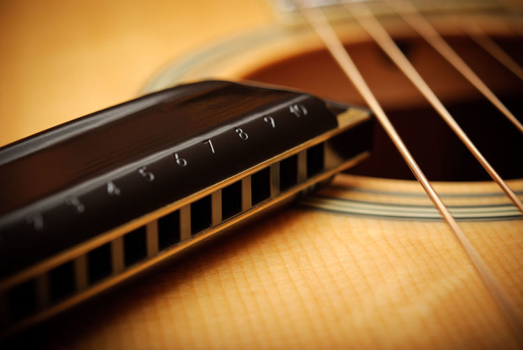 Close-up of guitar with harmonica on table
