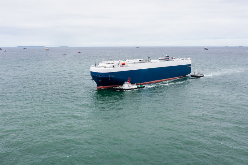 Roll-on roll-of ship loading new cars line up . automotive container carriers floating in sea, 