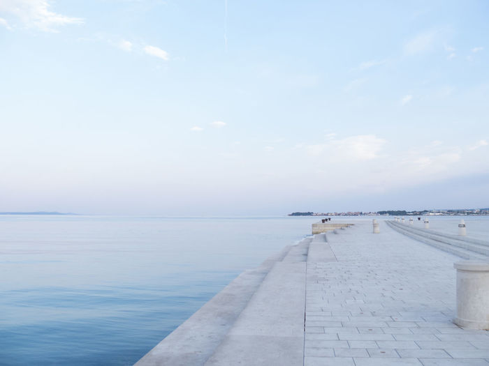 Empty jetty leading to calm blue sea