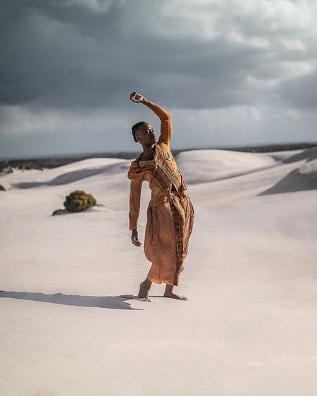 Full length of young man wearing traditional clothing standing at desert