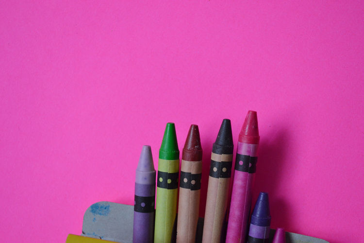 Close-up of colored pencils against pink background