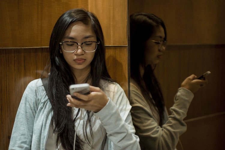Teenage girl using mobile phone indoors