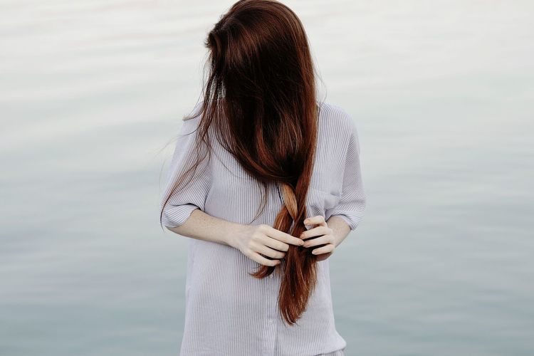 Young woman doing her hair against lake
