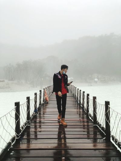 Full length of man standing on pier over lake during winter