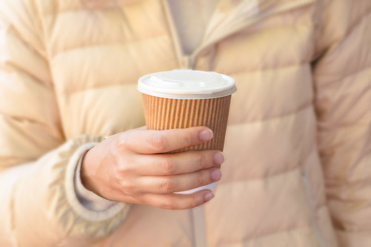 Close-up of woman holding eco-friendly cup of coffee to go, street coffee, no plastic