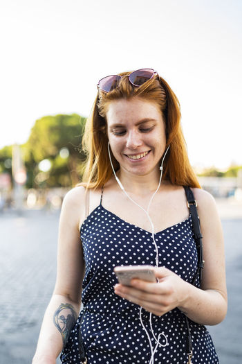 Happy woman listening to music and messaging on smartphone