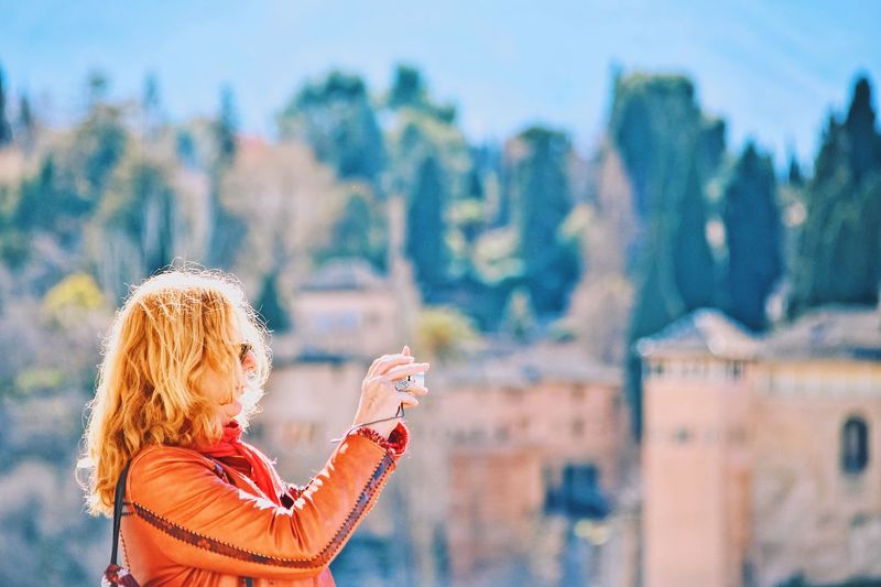 Portrait of woman with arms raised against mountain