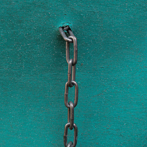Close-up of chain hanging against blue wall