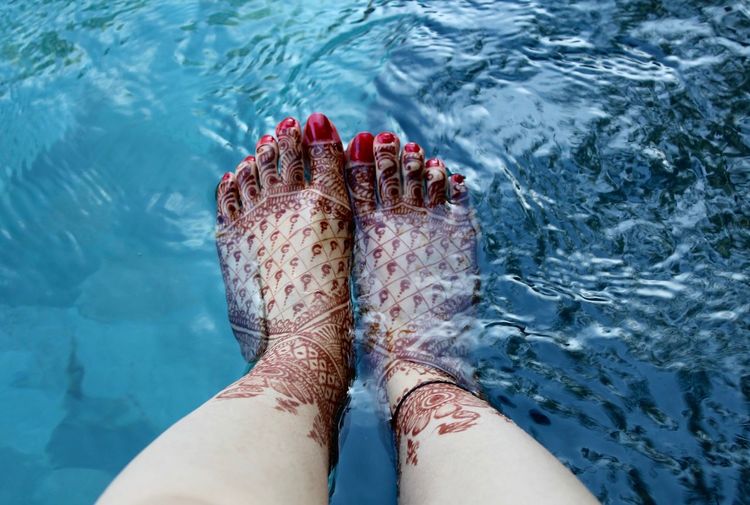 Low section of woman with henna tattoo in swimming pool