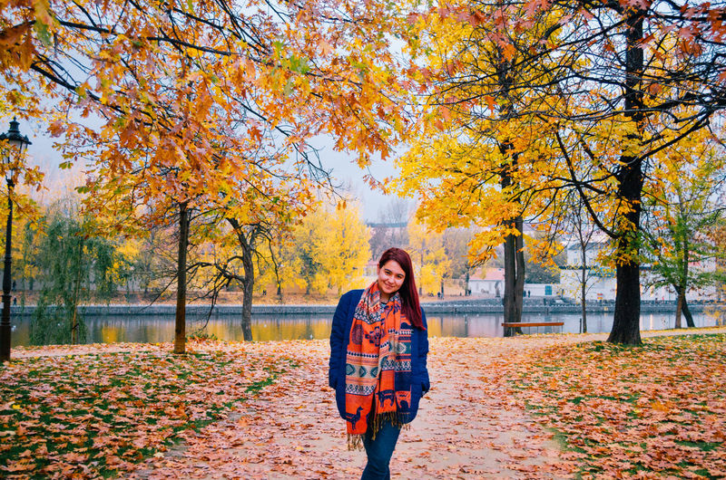 Young woman standing by trees during autumn