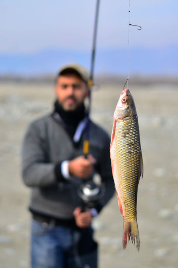 Man holding fish hanging from fishing rod