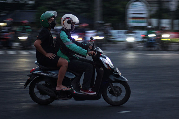 People riding motorcycle on road in city