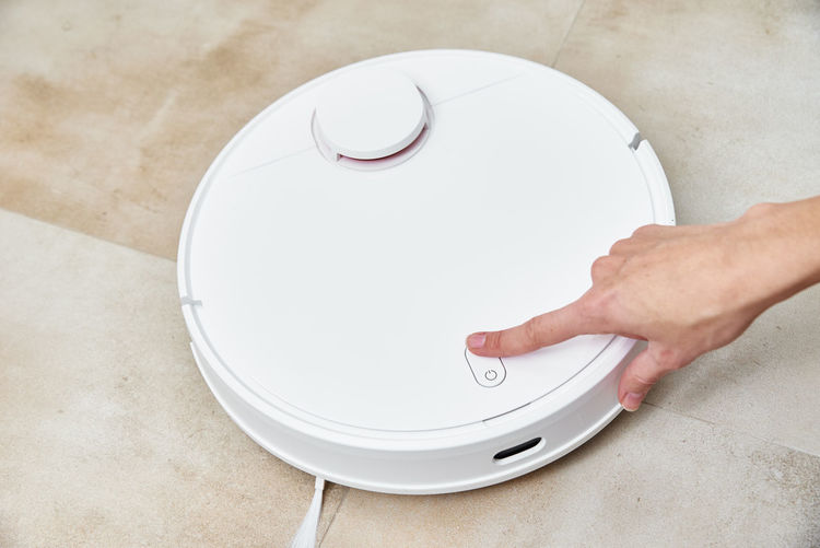 Hand push start button on the robot vacuum cleaner. modern smart household