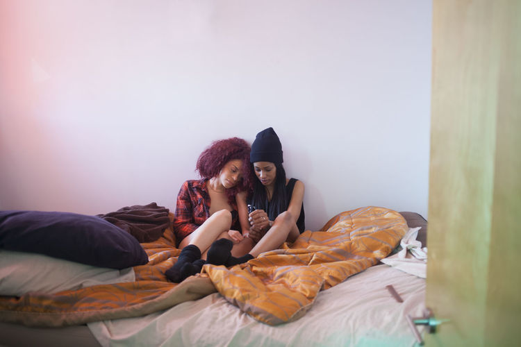 Young women sitting in bed together