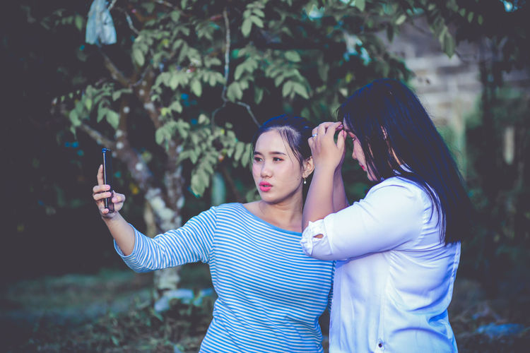 Young woman photographing while standing on mobile phone