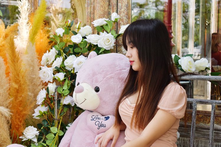 Close-up of woman sitting with teddy bear outdoors