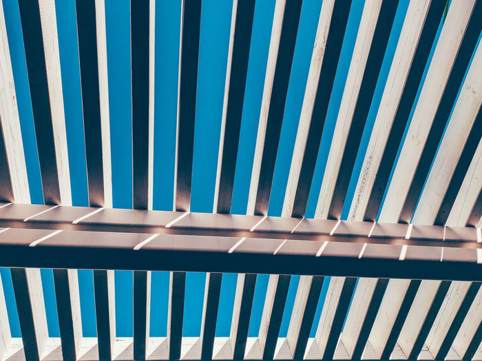 Low angle view of railing against blue sky