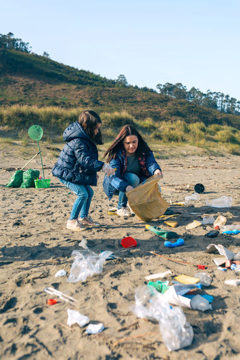 Mother and daughter picking garbage at beach