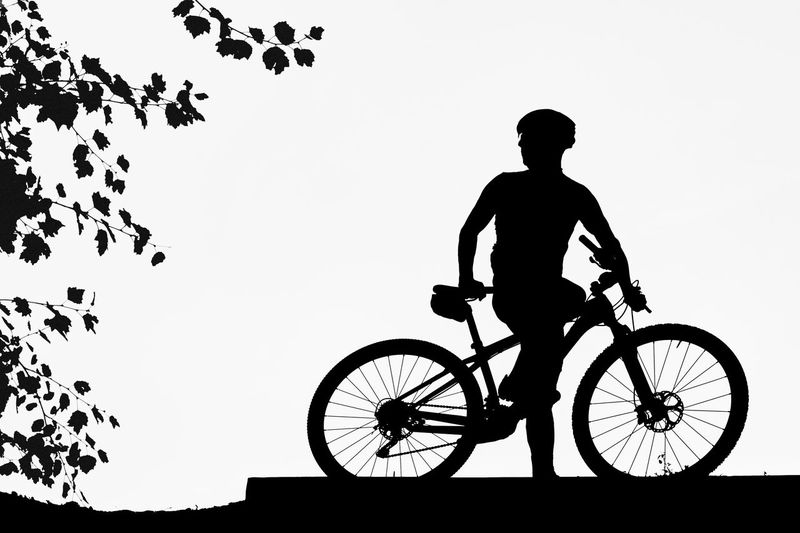 Silhouette man riding bicycle against clear sky