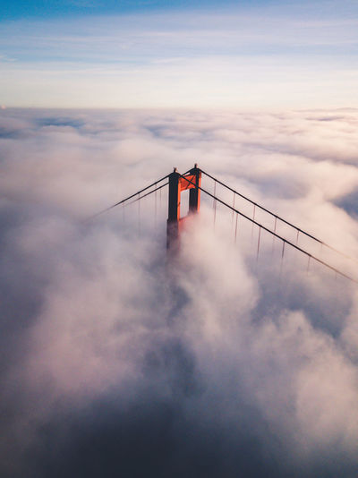 High angle view of suspension bridge against cloudy sky during sunset