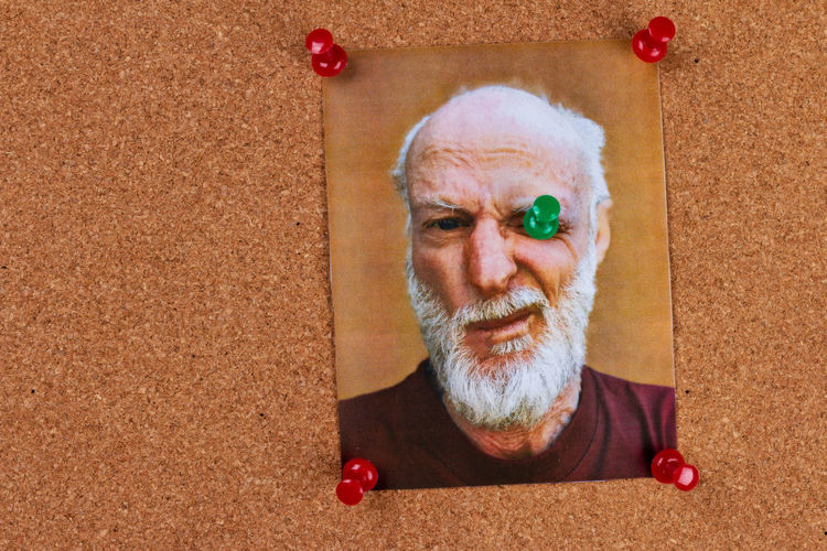 Close-up of senior man making face in photograph on wall