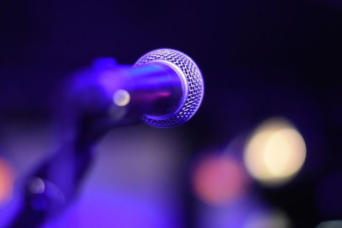 Close-up of microphone against illuminated stage lights