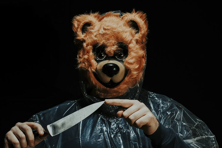 Close-up of evil killer bear with knife against black background