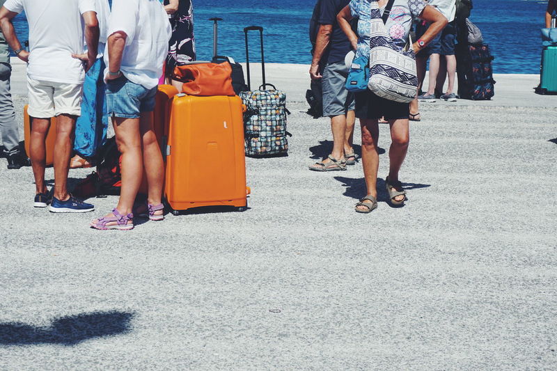 Low section of people with luggage against sea