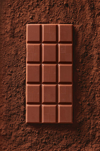 Directly above shot of chocolate bar on cocoa powder