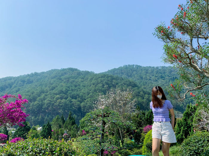 Woman standing by plants against clear sky