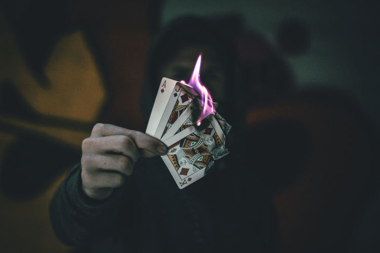 Close-up of person holding burning cards