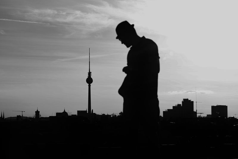 Silhouette of man and cityscape against sky during sunset