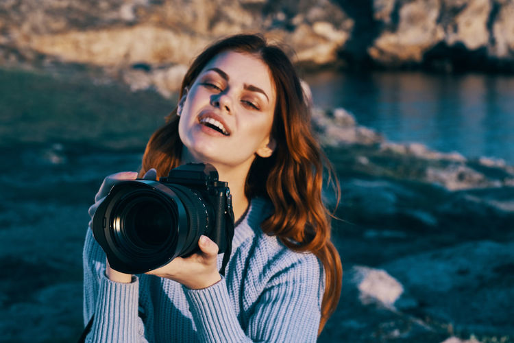 Portrait of beautiful young woman holding camera
