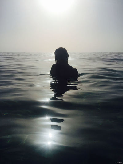 Silhouette woman swimming in sea against sky