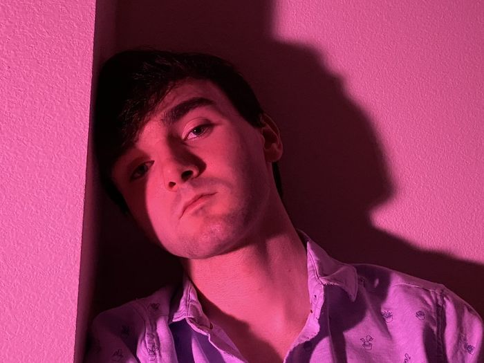 Portrait of young man against pink wall
