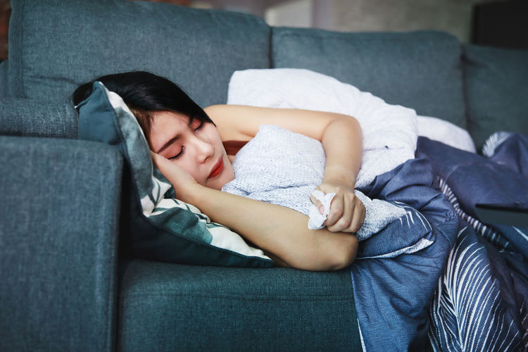 Full length of woman sleeping on sofa at home