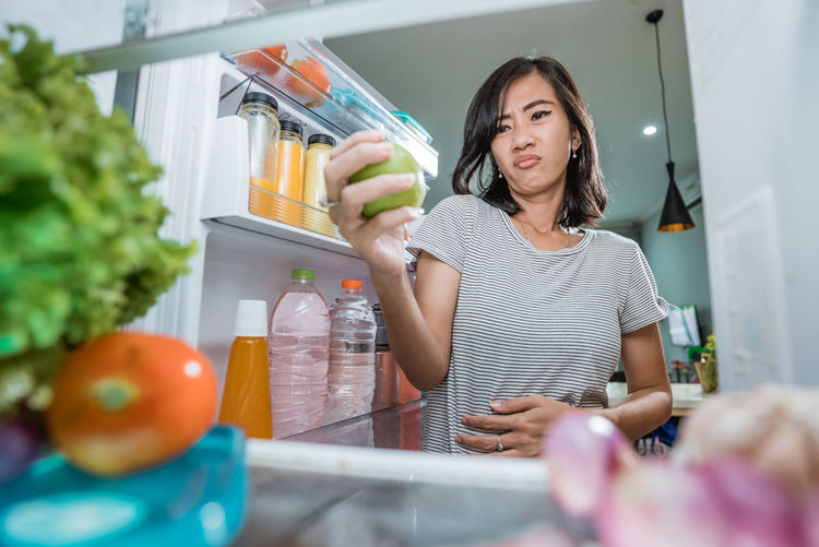 Young woman standing by food at home